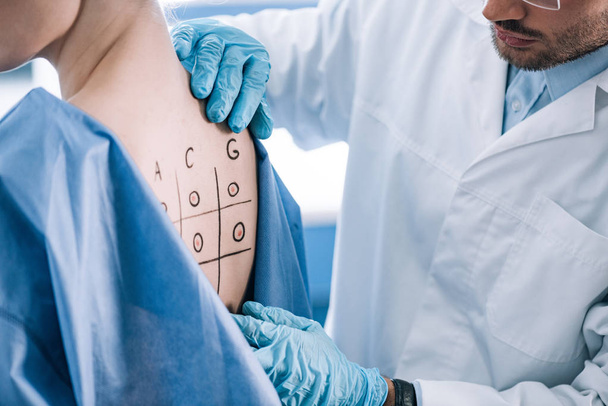cropped view of allergist touching marked back with numbers and letters - Photo, Image