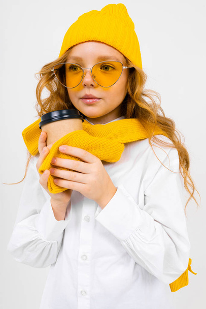 fashionable schoolgirl posing with coffee cup in studio on light background  - Foto, Imagem