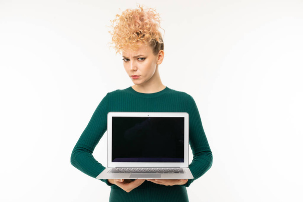 fiatal nő zöld ruhában pózol laptop ellen fehér háttér   - Fotó, kép