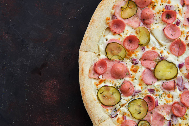 Close up view of pizza with frankfurter, ham, pickled cucumber and onion - Photo, image