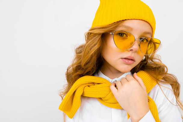 close up retrato de linda menina vestindo cachecol amarelo, chapéu e óculos
  - Foto, Imagem