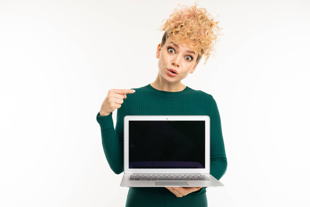 young woman in green dress posing with laptop against white background   - Foto, immagini