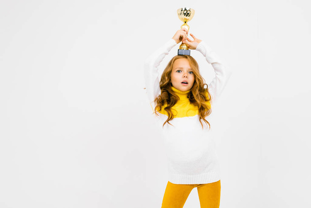 niedliches kleines Mädchen posiert mit Auszeichnung im Studio auf hellem Hintergrund  - Foto, Bild