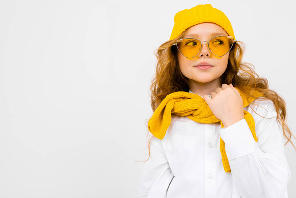közeli portré aranyos kislány visel sárga sál, kalap és szemüveg  - Fotó, kép