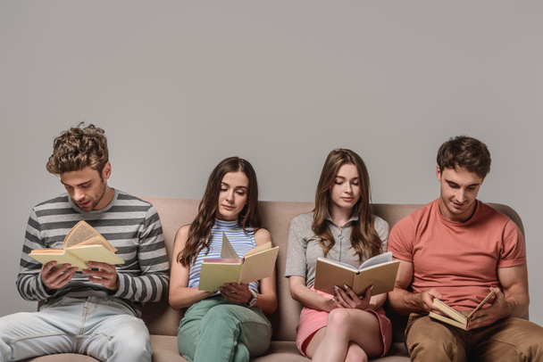 jóvenes amigos aburridos leyendo libros mientras están sentados en el sofá en gris
  - Foto, imagen