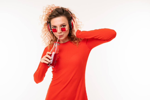 young woman in red dress posing with beverage against white background   - Фото, изображение