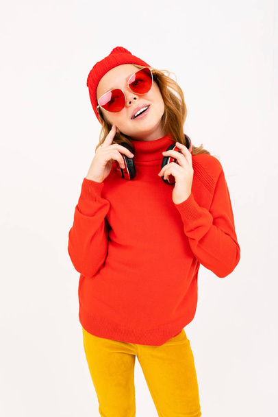 Kırmızı gözlüklü şirin kız stüdyoda kulaklıkla poz veriyor.  - Fotoğraf, Görsel