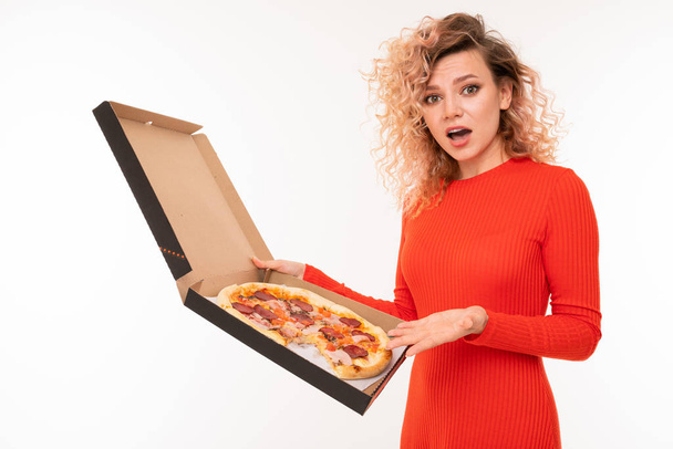 jonge vrouw in rode jurk poseren met pizza tegen witte achtergrond   - Foto, afbeelding