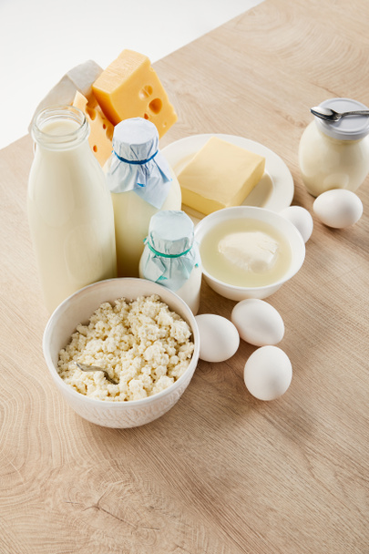 νόστιμα φρέσκα γαλακτοκομικά προϊόντα και αυγά σε ξύλινο τραπέζι απομονώνονται σε λευκό - Φωτογραφία, εικόνα