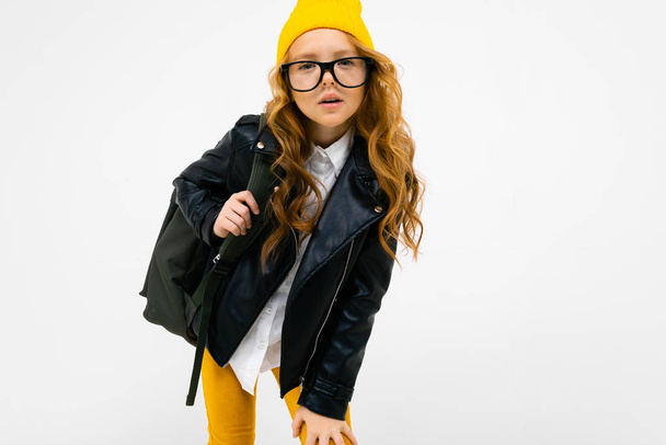 cool little girl in laser jacket posing with backpack in studio on light background  - Photo, Image