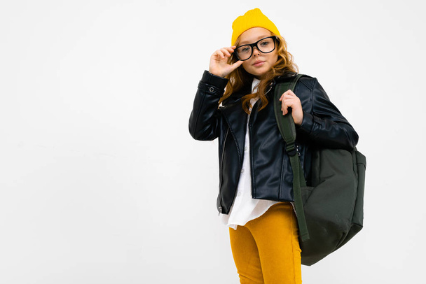 cool little girl in laser jacket posing with backpack in studio on light background  - Fotó, kép