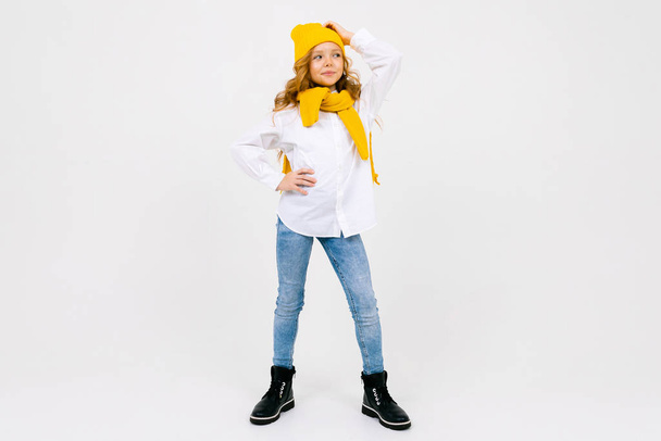 Sarı şapka ve eşarp takmış, açık arkaplanda poz veren zarif küçük bir kızın portresi.  - Fotoğraf, Görsel