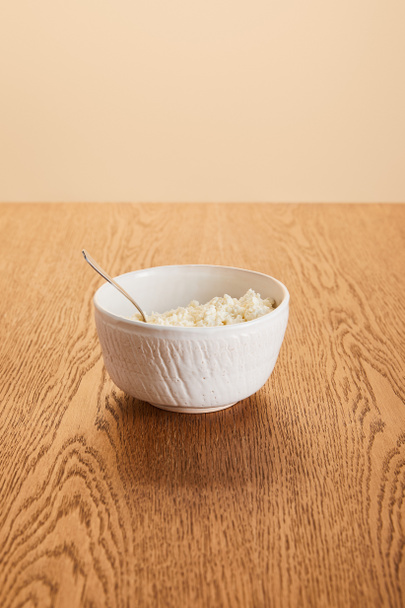 λευκό φρέσκο βιολογικό τυρί cottage σε μπολ σε ρουστίκ ξύλινο τραπέζι απομονωμένο σε μπεζ - Φωτογραφία, εικόνα