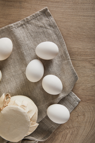 bovenaanzicht van eieren en melk op houten tafel met servet - Foto, afbeelding