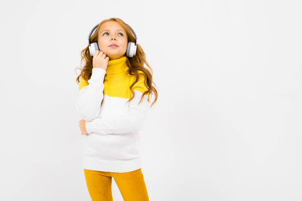 χαριτωμένο κοριτσάκι με ακουστικά που ποζάρουν στο στούντιο στο φως φόντο  - Φωτογραφία, εικόνα