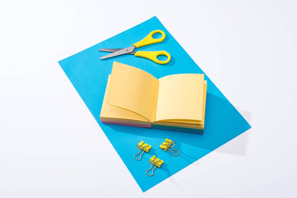 high angle view of notebook, scissors, binder clips and paper on white background  - Photo, Image