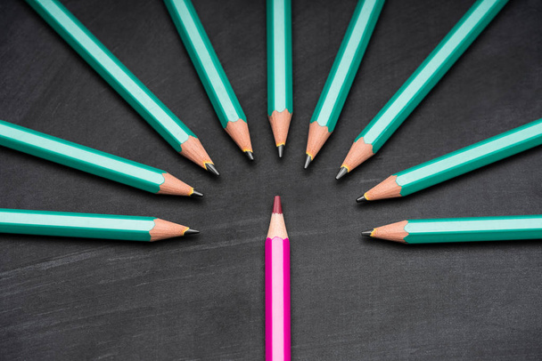 Pink Colored Pencil Surrounded With Green Lead Pencils On Black Chalkboard - Photo, Image