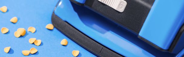 panoramic shot of holepunch with paper circles on blue background  - Foto, Imagem