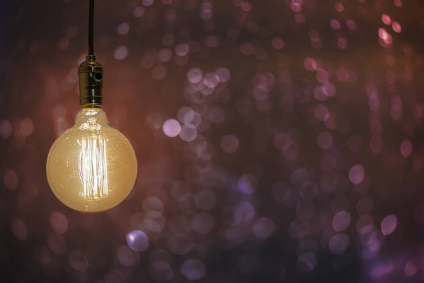 Vintage lit light bulb isolated on a colorful blurred background - perfect for a background - Photo, Image