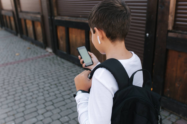 ワイヤレスヘッドフォンを備えた10代の少年のモックアップは、携帯電話を使用しています。緑の画面 - 写真・画像