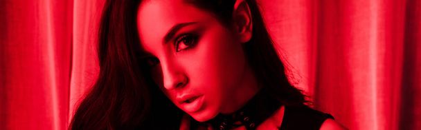panoramic shot of beautiful passionate young woman posing in red light - Photo, Image