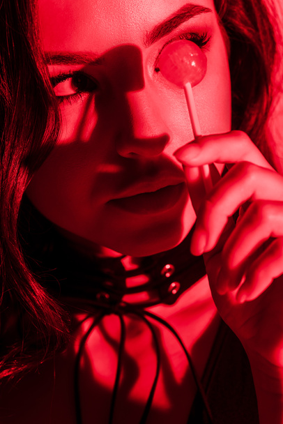 krásná vášnivá žena jíst lízátko v červeném světle - Fotografie, Obrázek