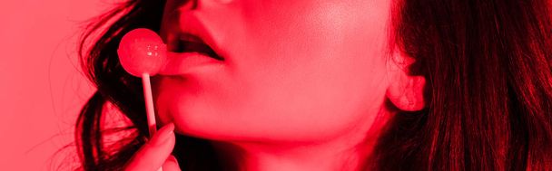kivágott kilátás szexi lány eszik nyalóka piros fényben, panoráma lövés - Fotó, kép