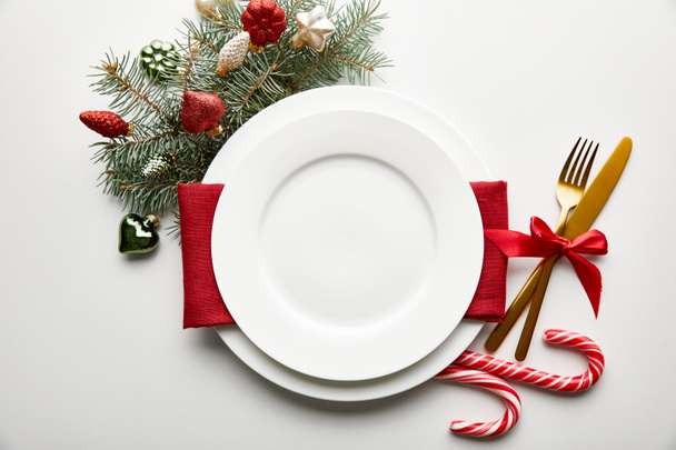 top view of festive Christmas table setting on white background with decoration, pine branch and candies - Photo, Image