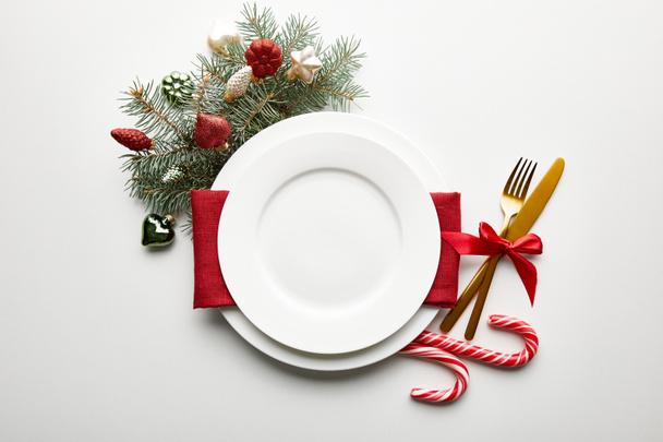 top view of festive Christmas table setting on white background with decoration, pine branch and candies - Foto, Bild