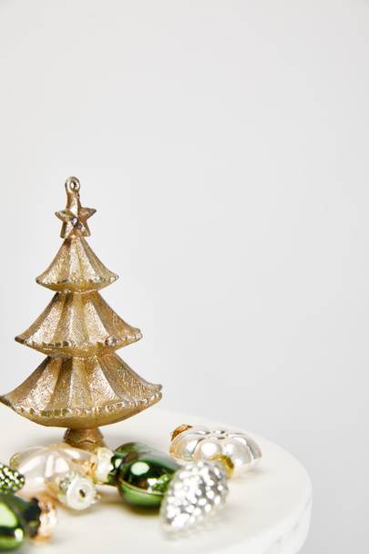 brillante árbol de Navidad y bolas en la superficie blanca aislado en gris
 - Foto, Imagen