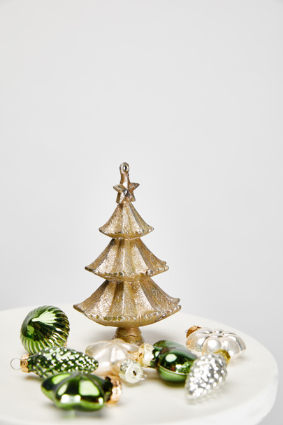 lesklý vánoční stromek a cetky na bílém povrchu izolované na šedé - Fotografie, Obrázek