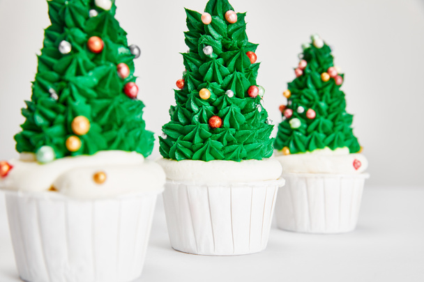 селективный фокус вкусные кексы Рождественские елки подряд на белой поверхности изолированы на сером
 - Фото, изображение