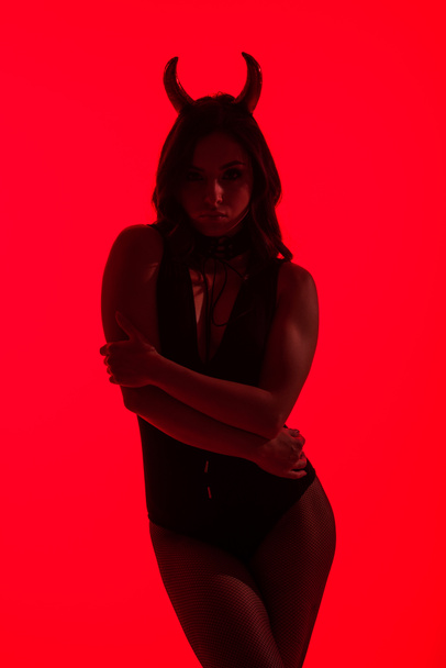 silhouette of sexy woman in Devil costume, isolated on red - Foto, imagen