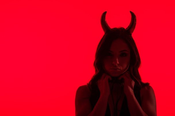 silhouette of seductive woman in Devil costume, isolated on red - Foto, imagen