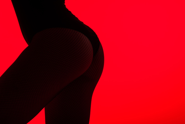 black silhouette of buttocks of sensual girl, isolated on red - Foto, afbeelding
