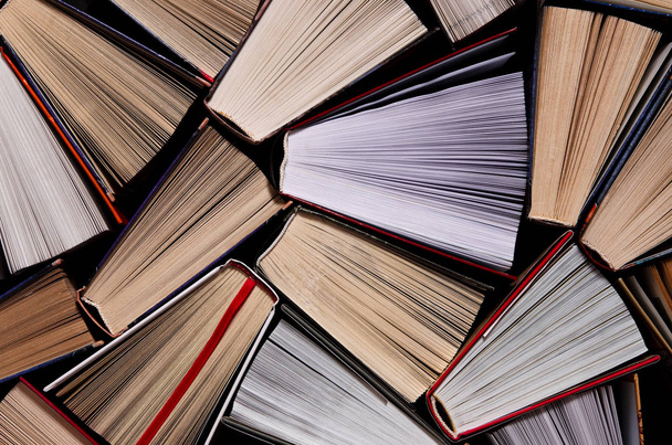 Βιβλία. Πολλά πολύχρωμα χοντρά ανοιχτά βιβλία στέκονται σε σκοτεινό φόντο - Φωτογραφία, εικόνα