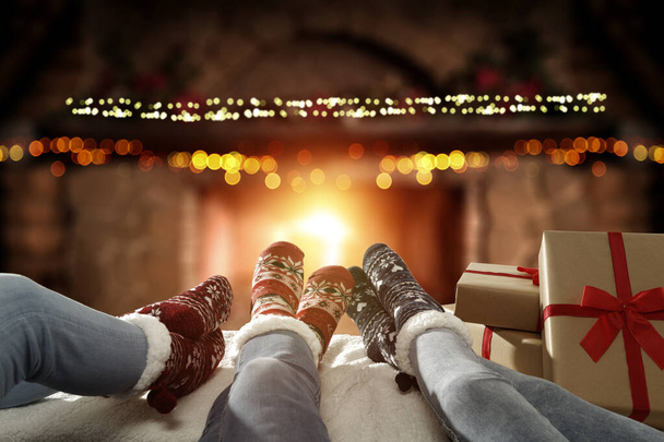 Woman legs with christms woolen socks and free space for your decoration. Home interior with fireplace and warm orange color of fire.Copy space and december xmas time.  - Foto, immagini