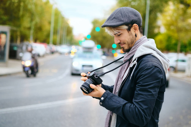Photographe de rue Hipster examinant des images sur l'affichage d'appareil photo sans miroir
 - Photo, image