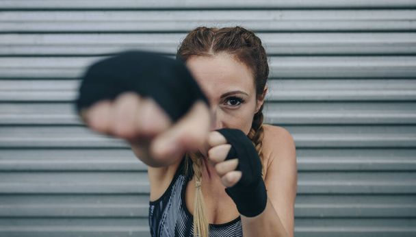 Sportovní žena dívá na kameru a punching - Fotografie, Obrázek