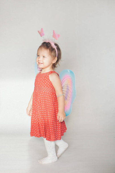 A little girl with colorful wings. A child in a fairy costume. Christmas concept, mystical creatures, Halloween, carnival, costume party - Foto, Imagen