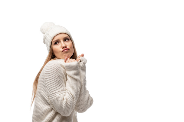 atractiva mujer escéptica posando en suéter y sombrero de punto blanco, aislado en blanco
 - Foto, imagen