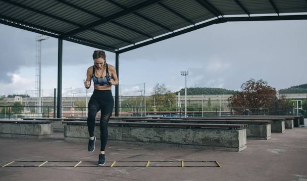 Sportswoman sautant sur une échelle d'agilité - Photo, image