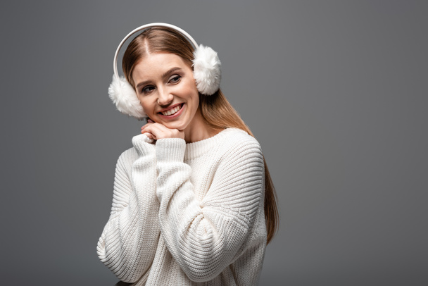 smiling woman posing in white sweater and ear warmers, isolated on grey - Photo, Image