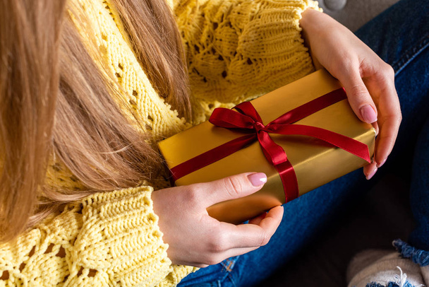 cropped view of woman in yellow sweater holding christmas present - Фото, зображення