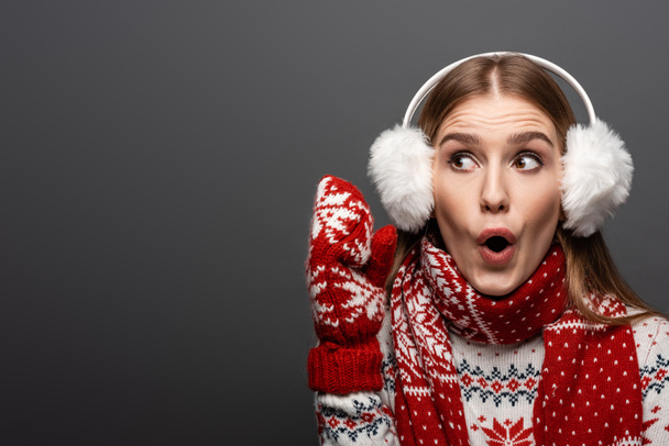 mujer excitada en jersey de Navidad, bufanda, manoplas y orejeras, aislada en gris
 - Foto, imagen