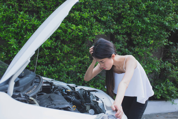 Азійська жінка, яка зазнала сильного стресу біля розбитої машини, розпачливо переживає проблеми з автомобілем. - Фото, зображення