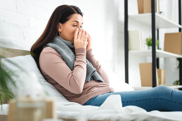 sick woman in scarf with runny nose holding napkin at home - Photo, image