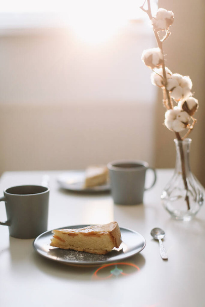 Piece of apple pie on plate with cup of coffee on white table. Breakfast with coffee and cake in cafe. food photography.  - Фото, изображение
