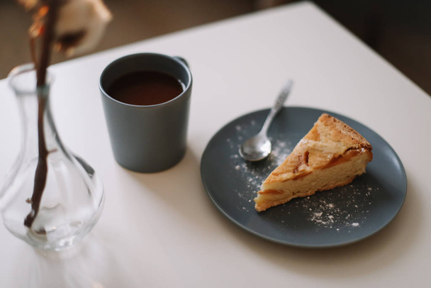 Piece of apple pie on plate with cup of coffee on white table. Breakfast with coffee and cake in cafe. food photography.  - Foto, Imagen