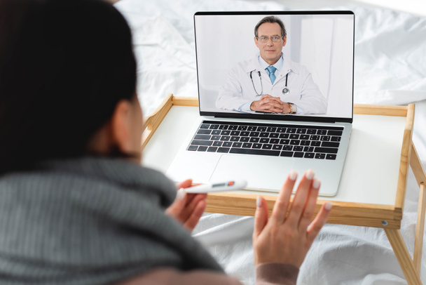 vista recortada de la mujer enferma que tiene consulta en línea con el médico masculino en el ordenador portátil
 - Foto, imagen